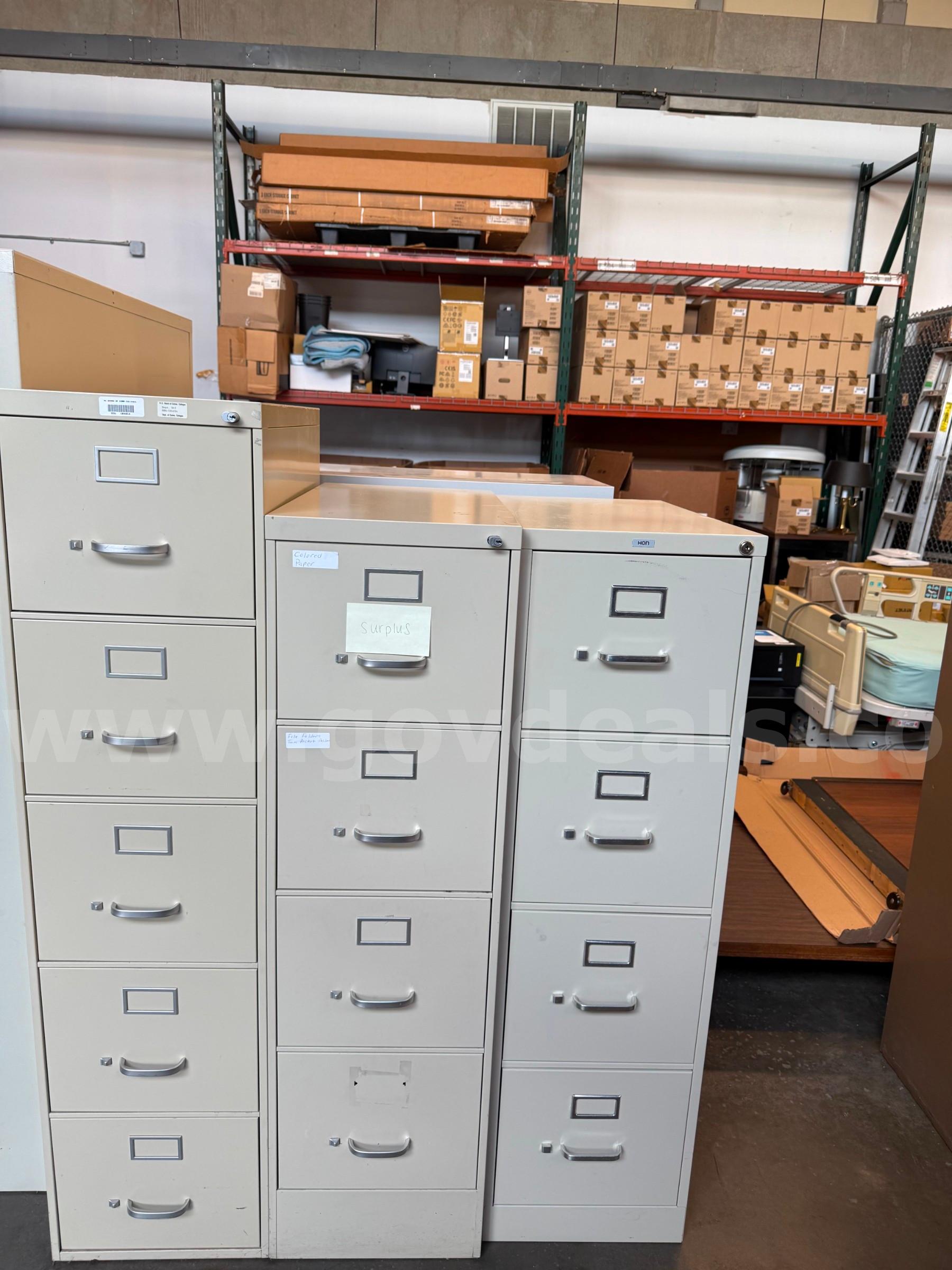 Lot includes three (3) four-drawer vertical metal filing cabinets in assorted gray finishes.  These filing cabinets were   Government Surplus Auction - Primary Photo